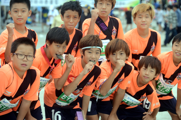 2012안산 바닷길 환경마라톤대회에 참가한 초등학교 축구부가 완주메달을 들어보이고 있다.