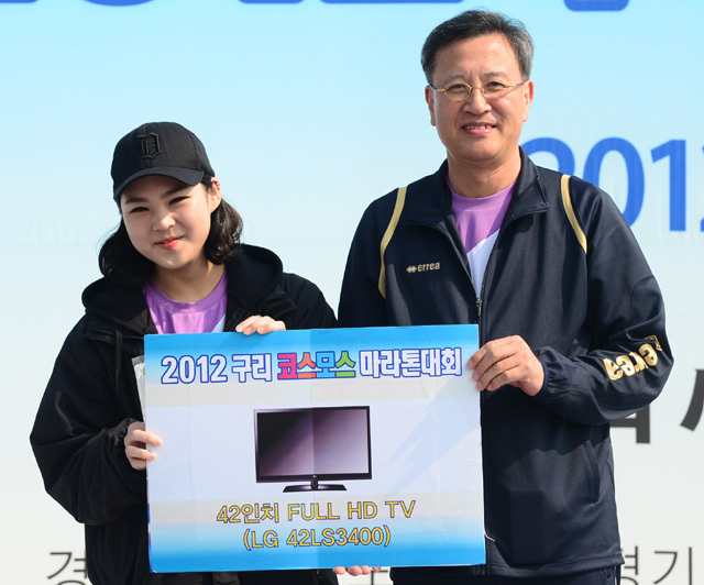 2012 구리 코스모스 마라톤대회가 열린 14일 구리 한강시민공원에서 이승규 경기일보 전무이사가 경품에 당첨된 참가자에게 LED 42인치 TV를 전달하고 있다.  추상철기자 scchoo@kyeonggi.com