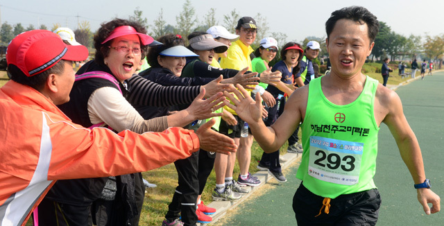 2012 구리 코스모스 마라톤대회가 열린 14일 구리 한강시민공원에서 하프부문에 참가한 한 마라토너가 동료들의 응원을 받으며 역주하고 있다. 추상철기자 scchoo@kyeonggi.com