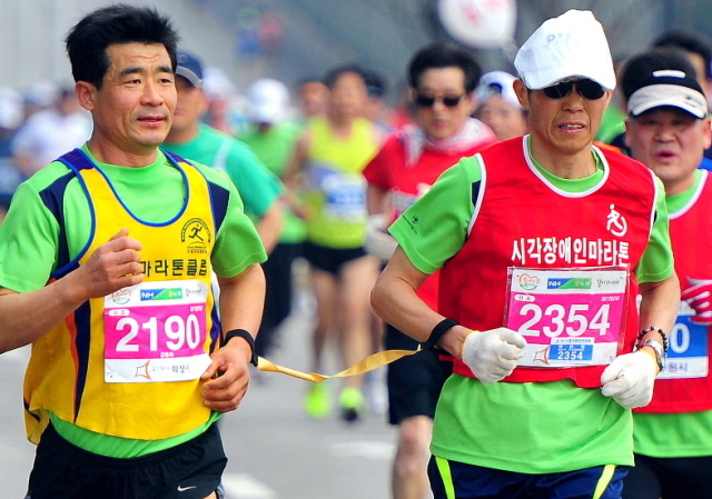 14일 제11회 경기마라톤 하프코스에 참가한 한 시각장애 선수가 끈으로 연결한 도우미와 함께 힘차게 달려 나가고 있다. 특별취재반