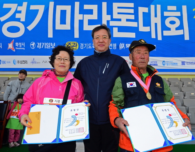 경기일보가 주최한 제11회 경기마라톤대회가 열린 14일 수원 종합운동장에서 경기일보 이승규 전무이사가 최고령 참가자에게 상장을 수여한 후 기념촬영을 하고 있다. 특별취재반