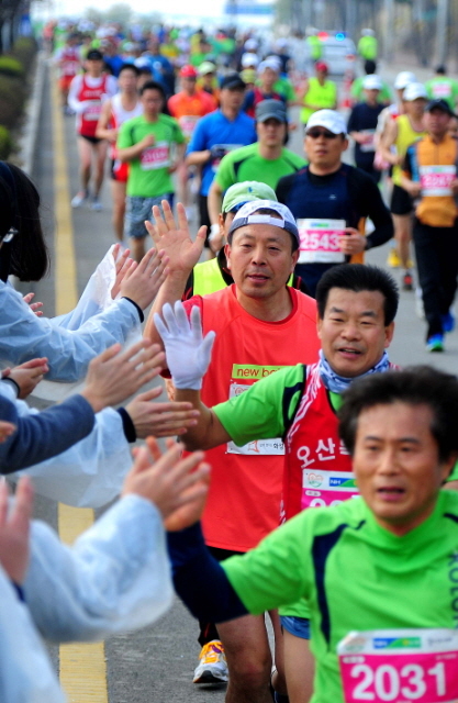 14일 제11회 경기마라톤에 참가한 하프코스 선수들이 1차 반환지점을 돌아 화이팅을 외치는 자원봉사 학생들과 하이파이브를 하고 있다. 특별취재반