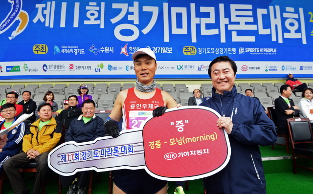 경기일보가 주최한 제11회 경기마라톤대회가 열린 14일 수원 종합운동장에서 이재율 경기도 경제부지사가 경품 1등 당첨자에게 자동차를 전달하고 있다. 특별취재반