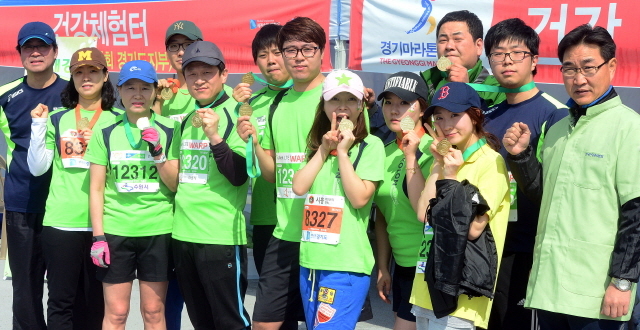 경기일보가 주최한 제11회 경기마라톤대회가 열린 14일 수원 종합운동장에서 한국건강관리협회 경기도지부 소속 참가자들이 완주메달을 들어보이며 파이팅을 외치고 있다. 특별취재반