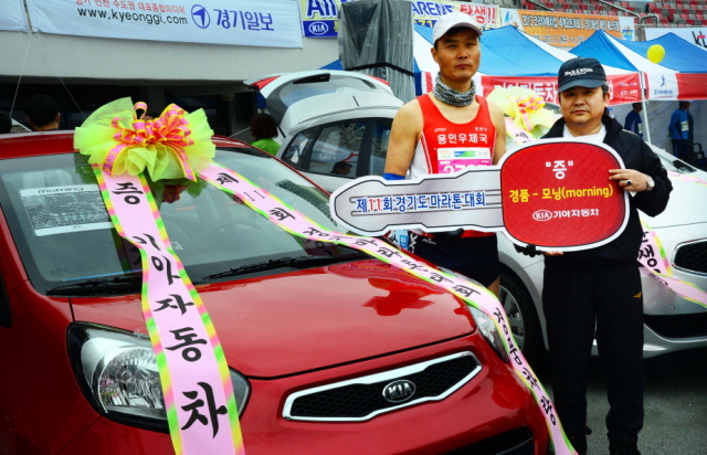 14일 수원종합운동장에서 열린 제11회 경기마라톤대회 자동차 경품당첨자가 단동호 기아차 화성총무안전실장과 기념촬영을 하고 있다 . 특별취재반