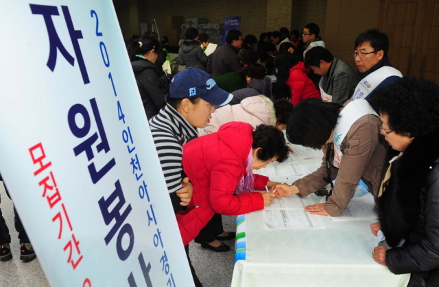 행사 참가에 앞서 자원봉사자들이 줄지어 내년 아시안게임 봉사 희망 서류를 작성하고 있다.장용준기자 jyjun@kyeonggi.com