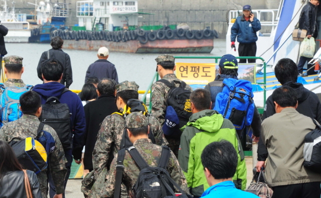 북한이 서해 북방한계선(NLL) 인근 해상에 해상사격을 실시한 31일 인천시 중구 연안여객터미널에서 주민들과 연평부대 장병들이 인천∼연평 항로의 유일한 여객선인 플라잉 카페리호로 승선하고 있다. 한편, 플라잉 카페리호는 공교롭게 출항시각이 북한의 사격시간과 겹치면서 운항통제가 발효돼 인천항을 출발하지 못했다.장용준기자 jyjun@kyeonggi.com