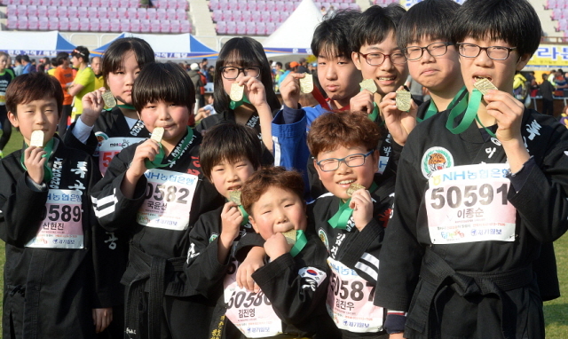 부천시와 경기일보가 공동주최한 제9회 부천복사골마라톤대회가 열린 16일 부천종합운동장에서 합기도 수련 학생들이 도복을 입고 완주 메달을 들어보이고 있다. 추상철기자