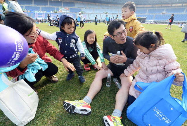 부천시와 경기일보가 공동주최한 제9회 부천복사골마라톤대회가 열린 16일 부천종합운동장에서 한 참가자 자녀들이 완주한 아빠의 어깨와 다리를 안마해 주고 있다. 추상철기자