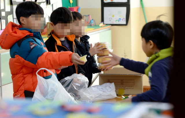 전국학교비정규직연대회의가 파업에 돌입한 20일 학교급식에 차질을 빚은 인천시의 한 초등학교 교실에서 점심시간을 맞은 학생들이 급식 대용으로 받은 빵과 우유를 나눠주고 있다. 장용준기자