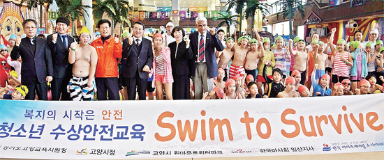 ▲ 고양 원마운트에서 열린 ‘Swim to Survive’ 시범 교육에 참가한 학생들이 시 공무원, 교육청LSK 관계자 등과 함께 파이팅을 외치며 기념촬영을 하고 있다.