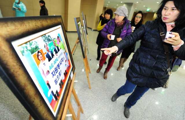 자원봉사자들이 행사장 입구에 전시된 활약상을 담은 사진전을 관람하고 있다.장용준기자