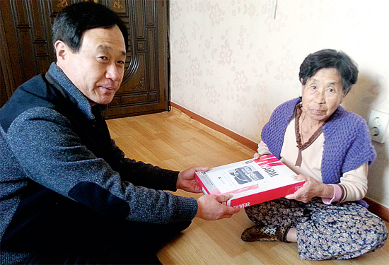 ▲ 이영진 동두천시 상패동주민센터 동장(왼쪽)이 이건식씨가 불우이웃을 위해 기증한 내복을 전달하고 있다.