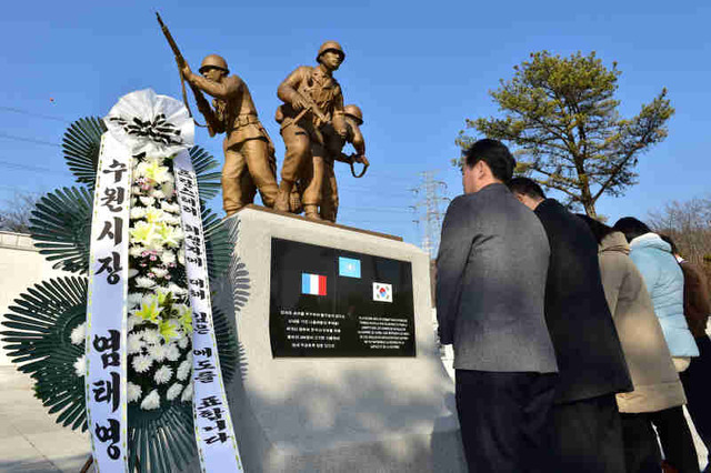 ▲ 수원시 관계자들이 12일 효행공원에 있는 프랑스군 한국전쟁 참전기념비 앞에 염태영 시장 명의의 조화를 설치하고 파리 총격 테러 희생자를 애도하고 있다.  ♣♣수원시 제공