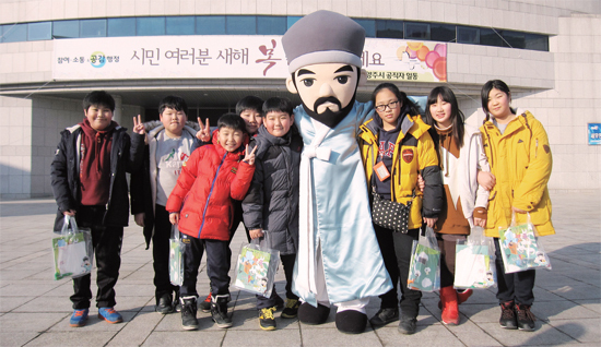 ▲ ‘다산 할아버지와 함께하는 남양주시청 견학프로그램’에 참가한 남양주 진건초 어린이들이 시청 앞 광장에서 다산 정약용 선생 캐릭터와 함께 기념촬영을 하고 있다