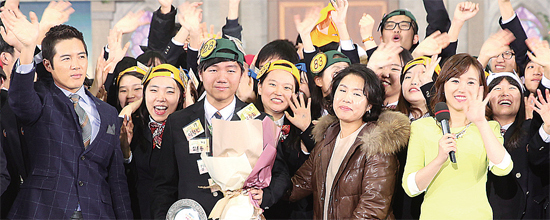 ▲ 파주 운정고 백승호군(가운데)의 제106대 골든 벨러 탄생을 축하하며 백 군의 어머니와 학생들이 KBS 도전 골든벨 사회자와 함께 환호하며 손을 흔들고 있다.  운정고 제공