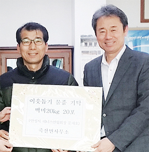 ▲ 문재호 회장(왼쪽)이 최근 유근석 면장을 만난 자리에서 쌀을 기부하고 있다.
