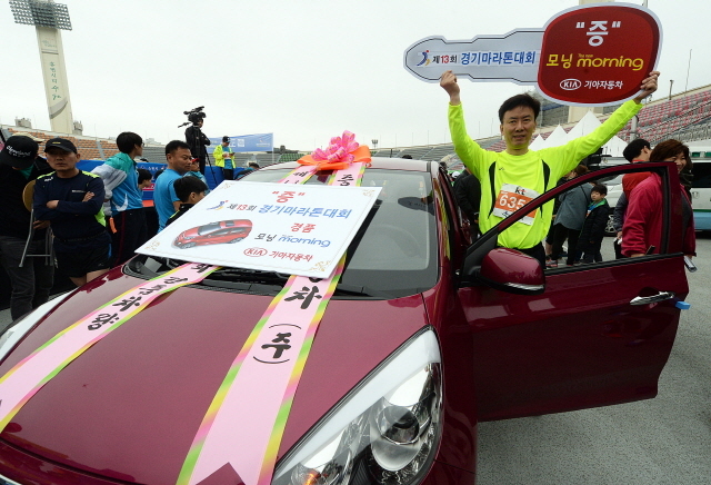 경기도와 수원시, 화성시, 경기일보가 공동주최한 제13회 경기마라톤대회가 열린 19일 수원종합운동장에서 경품 1등 기아자동차 모닝을 받은 참가자가 기념촬영을 하고 있다. 추상철기자