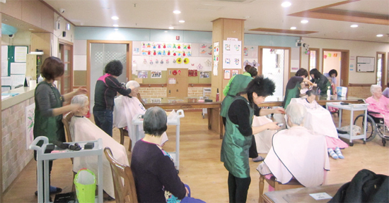 ▲ 안양시미용협회 회원들이 노인의 머리를 손질하고 있다.