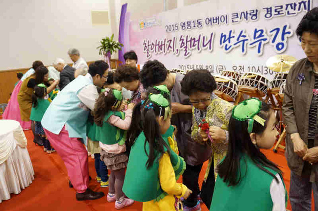 ▲ 수원시 영통1동 주민자치위원회가 지난 8일 영통체육문화센터에서 개최한 ‘제43회 어버이날 행사’에서 어린이들이 어르신들의 옷섶에 카네이션을 달아 드리고 있다.