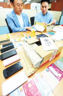 ▲ 중국에 거점을 두고 국내에서 활동하는 5개 보이스피싱 사기단을 검거한 인천지방경찰청 지능범죄수사대 직원이 21일 오전 청사내 사무실에서 증거품을 살펴보고 있다. 장용준기자