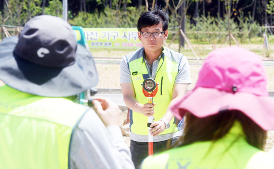 ▲ 확정측량중 지역내 설치된 구조물에 폴을 설치하고 좌표를 체크하는 일을 보조하고 있다.