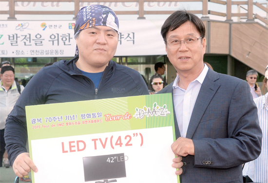 ▲ ‘Tour de DMZ 평화누리길 자전거 퍼레이드’의 부대행사로 치러진 경품행사에서 한 참가자가 42인치 LED TV를 받고 기념사진을 찍고 있다