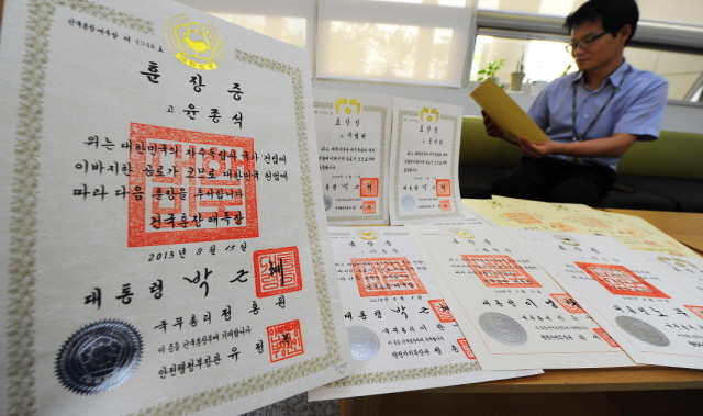 제70주년 광복절을 이틀 앞둔 13일 오후 세종시 종합청사내 국가보훈처 관계자가 인천경기지역 독립유공자들의 후손을 확인 못해 보관중인 훈장증서를 안타까운 마음으로 살펴보고 있다. 세종시=장용준기자