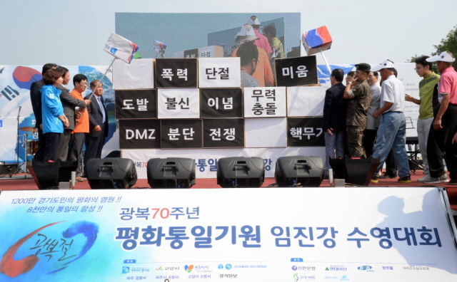 14일 파주시 적성면 주월리 임진강에서 열린 ‘광복70주년 평화통일기원 임진강 수영대회’개회식에서 이재홍 파주시장, 최성 고양시장,황진하 국회의원 , 양승환 경기도수영연합회장등 참석자들이 분단의 벽 허물기 퍼포먼스를 하고 있다. 전형민기자
