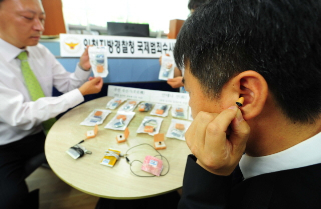 ▲ 스마트폰 애플리케이션과 무선 이어폰등의 첨단장비를 동원해 정보처리기능사 시험을 부정응시한 중국 조선족 일당들을 검거한 인천지방경찰청 국제범죄수사대 경찰들이 24일 오전 시연회에 앞서 증거품들을 살펴보고 있다. 장용준기자