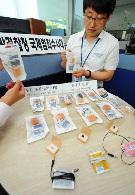 스마트폰 애플리케이션과 무선 이어폰등의 첨단장비를 동원해 정보처리기능사 시험을 부정응시한 중국 조선족 일당들을 검거한 인천지방경찰청 국제범죄수사대 경찰들이 24일 오전 시연회에 앞서 증거품들을 살펴보고 있다. 장용준기자