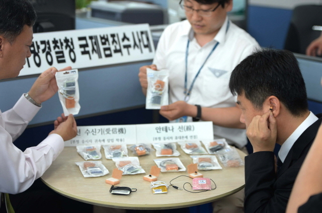 스마트폰 애플리케이션과 무선 이어폰등의 첨단장비를 동원해 정보처리기능사 시험을 부정응시한 중국 조선족 일당들을 검거한 인천지방경찰청 국제범죄수사대 경찰들이 24일 오전 시연회에 앞서 증거품들을 살펴보고 있다. 장용준기자