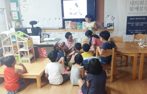 ▲ 지난달 14일 소만초등학교 돌봄교실에서 열린 ‘엄마들의 책 놀이터’ 프로젝트에서 일일교사로 분한배성호씨(가운데)가 저서 우리나라가 100명의 마을이라면 등 서적을 함께 읽으며 아이들과 상상의나래를 펴고 있다.