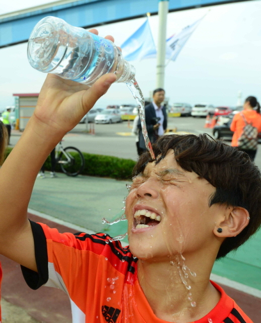 12일 오전 인천시 중구 월미도 순회도로에서 열린 제65주년 9.15 인천상륙작전 전승기념 마라톤대회에서 코스를 완주한 학생이 물을 머리 위로 뿌리며 더위를 식히고 있다. 김시범기자