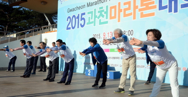 13일 과천 관문체육공원 운동장에서 열린 ‘2015 과천 마라톤 대회’에서 출발에 앞서 신계용 과천시장, 이순국 경기일보 사장 등 내빈들이 참가자들과 함께 몸풀기 운동을 하고 있다.전형민기자