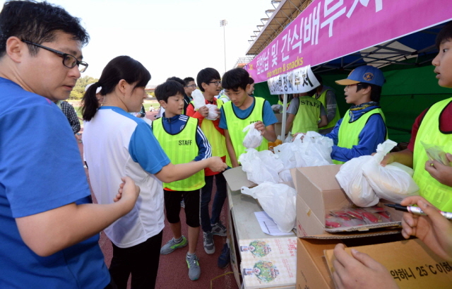 13일 과천 관문체육공원 운동장에서 열린 ‘2015 과천 마라톤 대회’에서  자원봉사자들이 참가자들에게 간식을 나누어 주고  있다.전형민기자