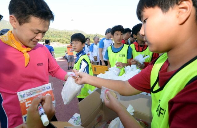 13일 과천 관문체육공원 운동장에서 열린 ‘2015 과천 마라톤 대회’에서  자원봉사자들이 참가자들에게 간식을 나누어 주고  있다.전형민기자