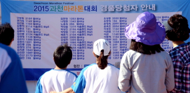 13일 과천 관문체육공원 운동장에서 열린 ‘2015 과천 마라톤 대회’에서 참가자들이 경품당첨자 안내판을 살펴보고  있다.전형민기자