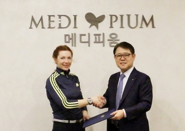▲ 의료법인 메디피움 장영준 이사장(사진 오른쪽)이 한국인으로 귀화한 러시아 출신 바이애슬론 선수 프롤리나 안나와 후원협약을 체결하고 기념사진을 찍고 있다
