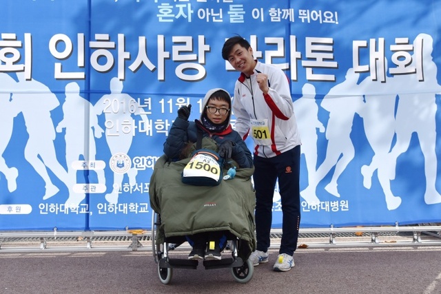 ▲ 지난 12일 인하대학교 대운동장에서 열린 제1회 인하사랑 마라톤 대회에 장애를 딛고 완주해 특별상을 수상한 설예훈군이 기념촬영을 하고 있다.(체어에 앉은 설예훈 학생과 도움을 준 박찬훈 학생)
