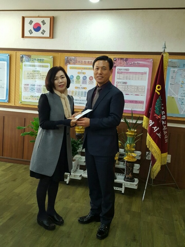 ▲ 강인덕 상임부회장이 박미자 교장에게 격려금을 전달하고 있다.