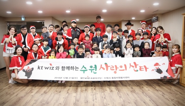 ▲ 산타 복장을 한 kt wiz 선수들과 팬, 자원봉사자들이 수원 동광원 보육 시설을 방문해 어린이들과 기념 촬영을 하고 있다. kt wiz 제공