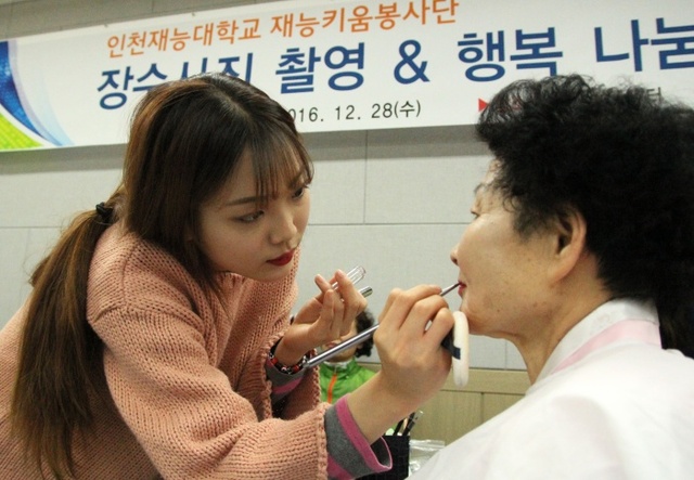 ▲ 재능대 재능키움봉사단원이 장수사진 촬영을 위한 메이크업을 도와주고 있다
