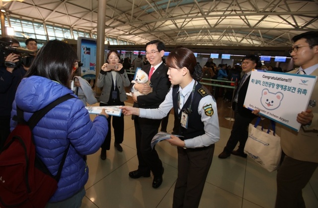 ▲ 인천공항공사 정일영 사장과 공항 보안검색요원들이 22일 오후 인천국제공항 여객터미널에서 SNS 스타 강아지 달리를 명예홍보견으로 임명하는 위촉식을 연 뒤 여객들에게 기내반입 금지물품 안내 팸플릿과 강아지 인형을 나누어주는 캠페인을 하고 있다. 사진 제공 인천공항공사