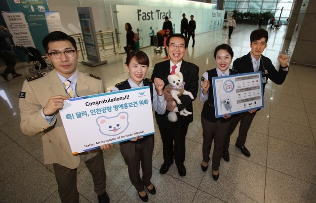 ▲ 인천공항공사 정일영 사장과 공항 보안검색요원들이 22일 오후 인천국제공항 여객터미널에서 SNS 스타 강아지 달리를 명예홍보견으로 임명하는 위촉식을 열고 기념사진을 찍고 있다. 사진 제공 인천공항공사
