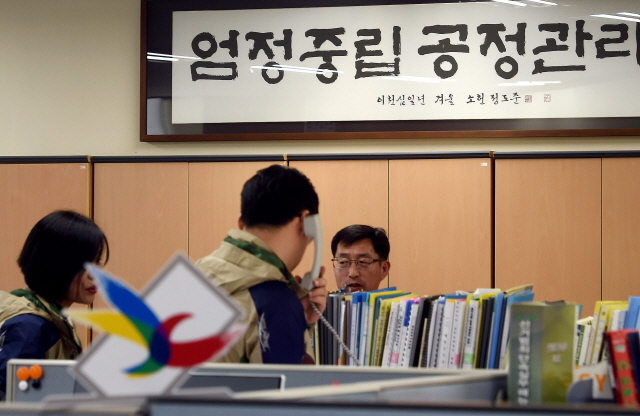 ▲ 10일 헌재의 박근혜 대통령 탄핵 인용 선고로 제19대 대통령 선거 일정이 본격 시작된 가운데 인천시 선관위 직원들이 벽에 걸린 '엄정중립' 액자 앞에서 바쁘게 걸려오는 문의전화를 받고 있다.장용준기자