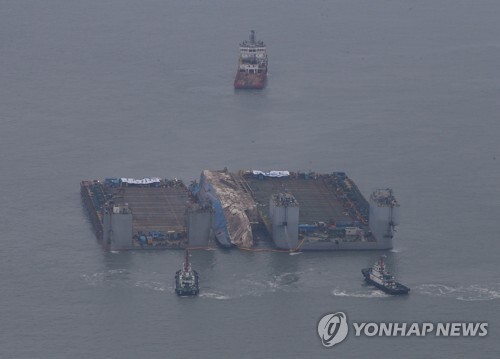 ▲ 24일 오후 전남 진도군 세월호 사고 해역에서 수면 위 13m까지 올라온 세월호가 2척의 잭킹바지선에 와이어로 묶여 반잠수식 선박으로 이동을 기다리고 있다. 해양수산부는 이날 오후 4시께 3㎞ 떨어진 곳에서 대기 중인 반잠수식 선박으로 본격 이동한다고 밝혔다. /연합
