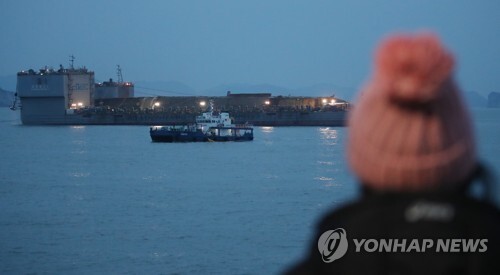▲ 24일 오후 전남 진도군 사고 해역에서 미수습자 가족이 세월호가 잭킹바지선과 예인선의 도움으로 반잠수선으로 이동하는 것을 보고 있다.  /연합