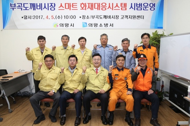 의왕시 전통시장인 부곡 도깨비시장 내에 화재가 발생할 경우 119 신고 없이도 소방차가 출동 가능한 스마트 화재 대응시스템이 전국 최초로 구축돼 시범 운영에 들어간 가운데, 김성제 시장이 5일 부곡 도깨비시장 고객지원센터 회의실에서 소방서와 시장 관계자와 함께 파이팅을 외치고 있다. 의왕시 제공