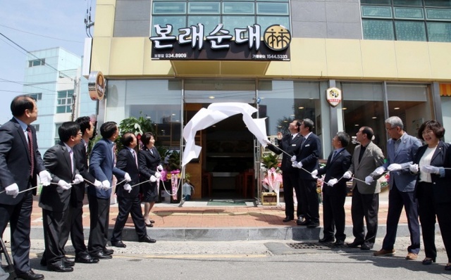 ▲ 한동 대표 브랜드 도드람이 자활지원사업 위탁운영 1호점인 ‘본래순대 보령점’ 오픈식에서 참석 내빈들이 현판식을 진행하고 있다.(사진=도드람)